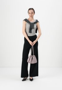 Canotta grigia chiaro a coste, pantaloni neri a gamba larga e tacchi neri. Tiene in mano una piccola borsa lavanda arricciata. Design semplice e pulito.