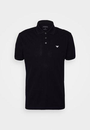 Polo nero con apertura a tre bottoni, maniche corte e un sottile logo ricamato sul lato sinistro del petto. Tessuto liscio, vestibilità classica.