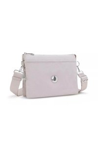 Ljusrosa crossbody-väska gjord av mjukt material, med en silverfärgad knappdetalj, justerbar rem och en dragkedjestängning upptill.