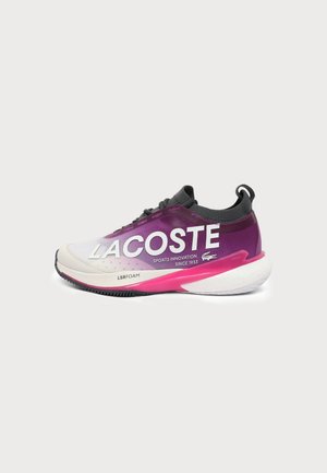 Basket Lacoste violette et blanche avec col noir, semelle intermédiaire rose et semelle blanche épaisse, avec grand logo Lacoste et texte "LSRFOAM" sur le côté.