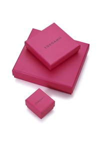 Drei pinkfarbene Geschenkboxen unterschiedlicher Größe gestapelt, mit glatter Oberfläche und auf den größeren Boxen ein schwarzes Logo gedruckt.