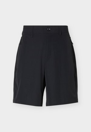 Sorte skræddersyede shorts med knap i taljen, bæltestropper og sidelommer med lynlås på en ensartet lyse baggrund.