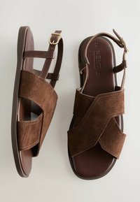 Braune Wildledersandalen mit überkreuzten Riemen und einem Knöchelverschluss. Glatter Schuhboden mit subtilen Dehnungsnähten. Klassisches offenes Design.