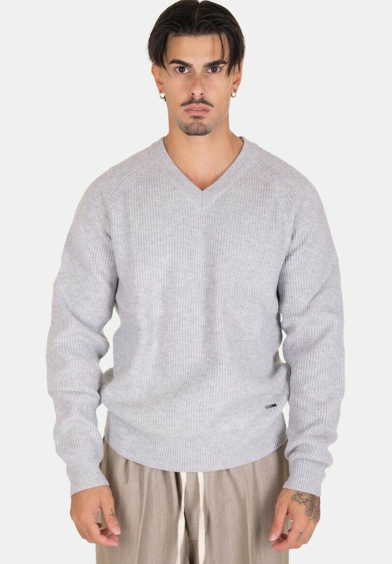 Maglione a coste grigio chiaro con scollatura a V, dotato di maniche lunghe e vita aderente. Texture notevole e accento di branding sottile.