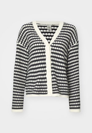 Pulover z gumbki, ki ima mornarsko modre in kremne stripe, pleteno teksturo, V-izrez in rebraste manšete. Štirje gumbi spredaj za zapiranje.