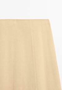 Beige fabric skirt section showing clean vertical seams and smooth texture against a white background.