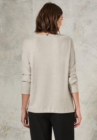 Pullover in beige chiaro, texturizzato, con vestibilità ampia, scollatura a barca, maniche a tre quarti e orlo curvo. Design semplice senza decorazioni.