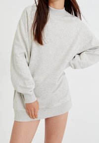 Sweatshirt oversize gris clair en matière douce. Caractérisé par un col montant, des poignets en maille côtelée et une coupe décontractée, arrivant jusqu'au milieu des cuisses.
