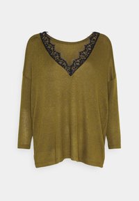 Top lungo a maniche lunghe di colore verde oliva con scollatura a V, rifinito con pizzo nero. Vestibilità morbida e tessuto testurizzato. Bordo leggermente sfilacciato.
