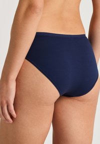 Culotte hipster en coton marine avec une texture lisse, taille mi-haute et une ceinture sans couture. Présente un design classique adapté à un usage quotidien.