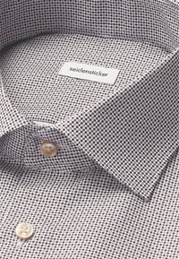 Camicia a maniche corte con bottoni caratterizzata da un piccolo motivo circolare in tonalità di viola e marrone, con colletto classico e etichetta con marchio.
