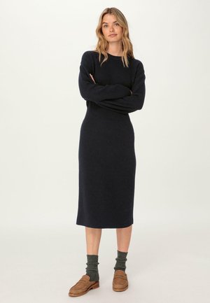 Robe midi tricotée navy à manches longues, texture côtelée, taille ajustée, col rond, accompagnée de chaussettes grises à côtes et de mocassins marron.