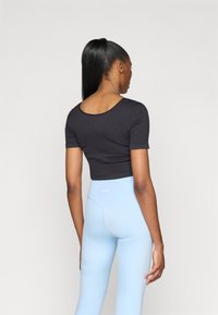 Black cropped t-shirt with short sleeves, paired with light blue high-waisted leggings featuring a subtle texture and branding on the waist.
