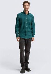 Zelená károvaná košeľa z mäkkej tkaniny, zapínaná na gombíky, s dlhými rukávmi, v páre s tmavými džínsami a čiernymi topánkami. Jednoduchý a priliehavý dizajn.