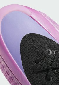 Fialové a růžové tenisky s texturovanou černou síťovinou, hladkými gumovými detaily a tkaničkami procházejícími kulatými očky. Vzorek podrážky ve tvaru včelího plástu.