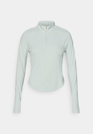 Světle zelený sportovní top s dlouhými rukávy, čtvrtinovým zipem a raglánovými rukávy. Hladká textura a jemné logo Nike na hrudi.