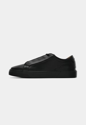 Black low-top sneaker with smooth leather upper, minimal stitching, and a rubber sole, shown in profile on a white background.
