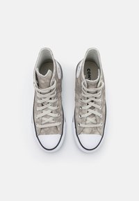 High-top sneakers made of light gray suede, featuring white rubber toe caps, flat laces, and black accents along the sole.
