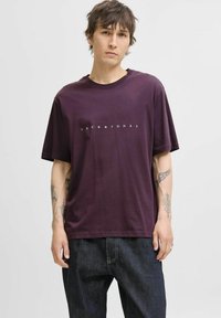 Ljubičasta pamučna majica s kratkim rukavima i okruglim izrezom, s bijelim logom "JACK & JONES" otisnutim preko prsnog dijela.