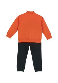 Sweat-shirt orange avec col montant et poignets côtelés, associé à un pantalon noir avec poignets côtelés aux chevilles. Les deux sont fabriqués en coton doux.