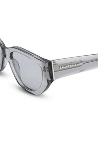 Occhiali da sole traslucidi grigi con un design arrotondato, dotati di lenti grigie e di un accento in argento lucido sulla tempia con il marchio "KAPTEN & SON".