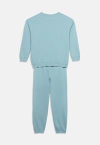 Σετ με γαλάζιο φούτερ μακρυμάνικο και αντίστοιχο παντελόνι φόρμας, με ριμπ τελείωμα στα μανίκια και τους αστραγάλους, εμφανιζόμενο από πίσω.