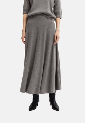 Langer grauer Strickrock mit einem dehnbaren Bund, der eine glatte Textur und einen leichten Schlag am Saum aufweist, ergänzt durch schwarze Stiefeletten.