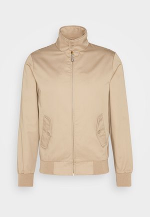 Giacca beige con collo alto, chiusura frontale con zip, due tasche laterali con bottone, polsini a coste e texture del tessuto liscia.