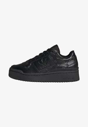 Zwarte Adidas lage sneaker met dikke zool, geperst trefoil-logo en stervormig patroon op de lederen bovenkant, zijwaarts bekeken.