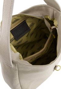 Lysebeige læderhåndtaske med en tekstureret ydre og et gult foret interiør med brandets logo. Inkluderer en lynlåslomme.