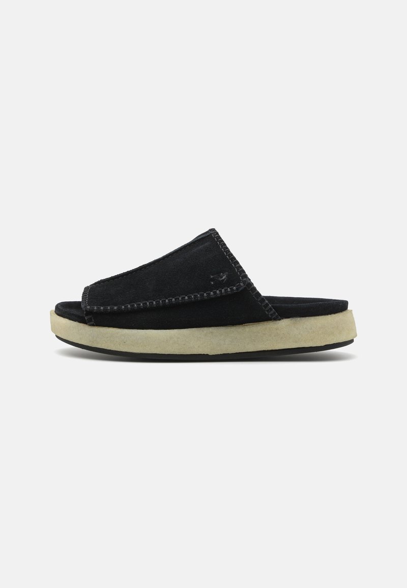 Infradito in suede nero con una forma morbida e arrotondata e suola in gomma di colore crema. Presenta cuciture a contrasto lungo i bordi.