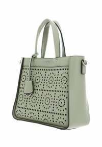 Sac à main en cuir vert avec motif floral découpé, design structuré, double poignée supérieure et étiquette amovible. Présente des accents noirs.