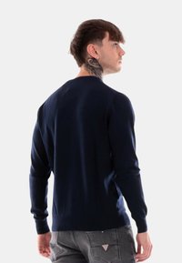 Maglione lavorato a maglia blu navy con maniche lunghe e scollo rotondo, caratterizzato da una texture liscia e un design aderente.