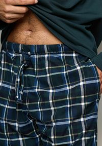 Pantalones de chándal de cuadros en azul marino, verde y blanco, con cintura elástica y textura de tela suave, que presentan un clásico patrón de cuadros.