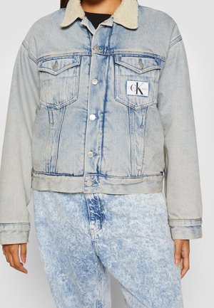 Světle modrá džínová bunda s límcem z beránka, zapínáním na knoflíky, dvěma kapsami na hrudi a logem Calvin Klein na levé kapse na hrudi.