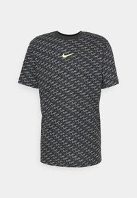 Černé tričko s krátkým rukávem s opakujícím se vlnitým vzorem. Na přední straně je malé žluté logo Nike. Bavlněný materiál s kulatým výstřihem.