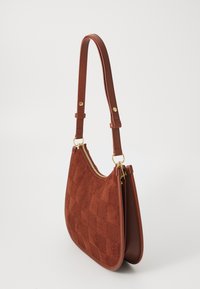 Braune Wildleder- und Leder-Schultertasche mit kariertem Muster, goldenem Reißverschluss und verstellbarem Tragegurt auf weißem Hintergrund.