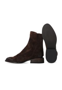 Brązowe zamszowe botki za kostkę o smukłym kroju, zaokrąglonym nosku i niskim, warstwowym obcasie. Podeszwa wykonana z czarnej gumy z teksturowanym wzorem zapewniającym przyczepność.