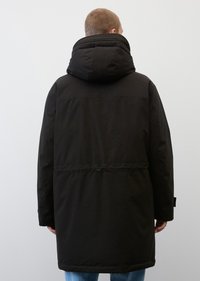 Schwarze, lange Daunenjacke mit einer großen Kapuze, tailliert und mit elastischen Bündchen. Glattes Material mit matter Oberfläche.