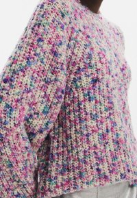 Pull en tricot épais présentant une palette de couleurs pastel avec des touches de rose, violet et bleu. Coupe ample et tissu texturé.