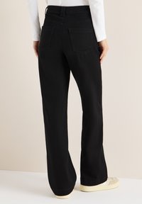 Pantalones negros de pierna ancha hechos de mezclilla con cintura alta, que cuentan con dos bolsillos traseros y una textura lisa. Acabados de dobladillo estándar.