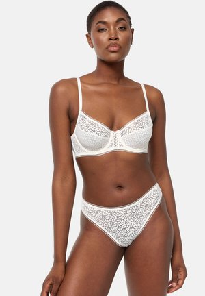 Bralette bianco in pizzo con motivo floreale, coppe morbide, spalline regolabili e coordinato di slip a vita alta con bordi ondulati.