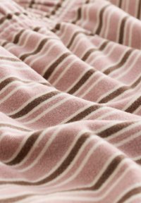 Material moale cu dungi orizontale roz, maro și alb, prezentat în pliuri apropiate care evidențiază textura și modelul.