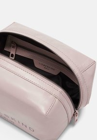 Borsa cosmetica in pelle rosa chiaro con chiusura a zip, caratterizzata da una superficie liscia e un interno nero. L'etichetta all'interno recita "LIEBESKIND BERLIN."