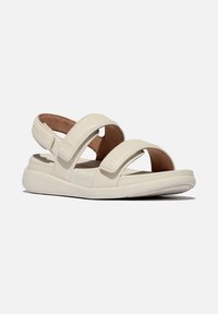 Beige sandaal met drie verstelbare banden, gemaakt van zacht leer, met een gevoerde inlegzool en een dikke, gestructureerde zool voor grip en comfort.