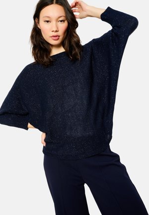 Maglione lavorato a maglia oversize blu navy con una finitura textured, maniche larghe e vestibilità comoda. Abbinato a pantaloni navy per un look coeso.