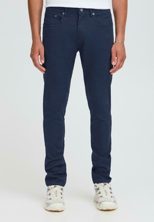 Marineblauwe jeans met een slim fit, gemaakt van denim. Bevat vijf zakken, een knoopsluiting en subtiele stiksels.