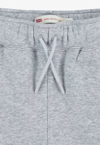 Pelēki platā kājās adīti bikses ar auklu jostasvieta un mīkstu tekstūru. Uz biksēm ir etiķete ar uzrakstu "Levi's Wide Leg Knit Pant".