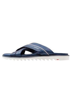Sandale en cuir bleu marine avec lanières croisées et semelle blanche texturée conçue pour un usage décontracté.