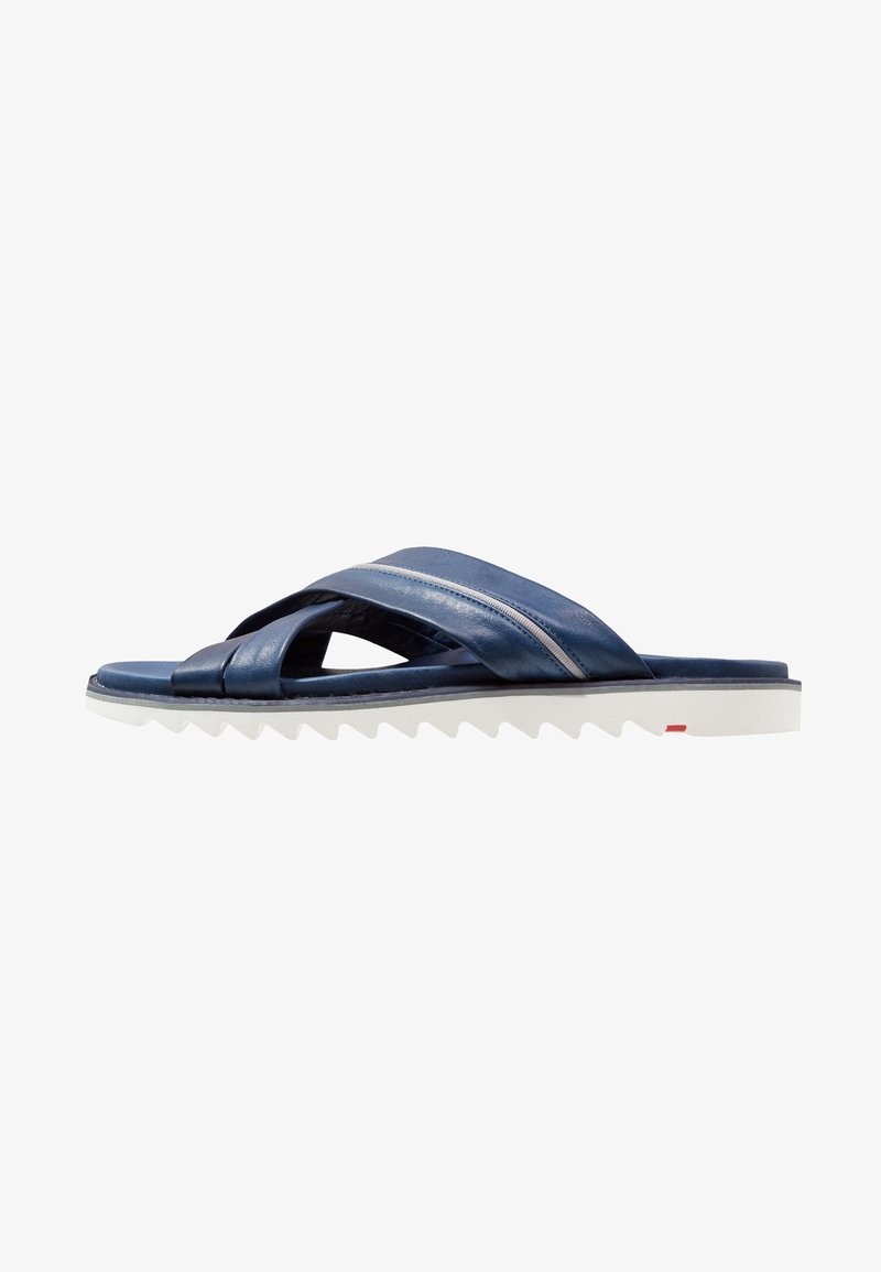 Sandale en cuir bleu marine avec lanières croisées et semelle blanche texturée conçue pour un usage décontracté.